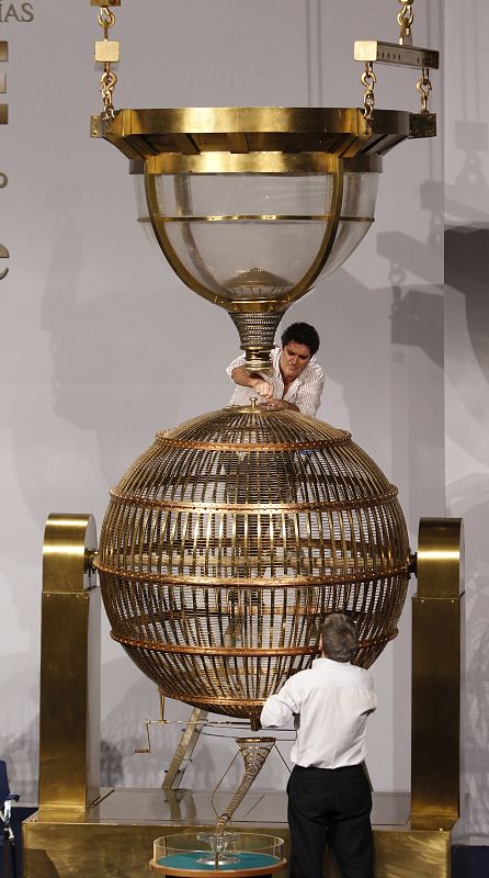 Dos operarios revisan el bombo de los números, que es el más grande y también será el más pesado -mil doscientos kilos- cuando su "estómago" haya engullido todas las bolas.