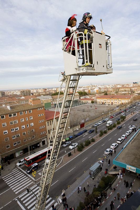 Bomberos de Zaragoza ayudan con su escalera mecánica a los Reyes Magos en su visita al Hospital Clínico de Zaragoza.