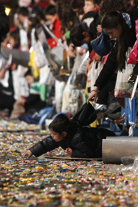 Un niño recoge caramelos en la Cabalgata de los Reyes Magos de Madrid.