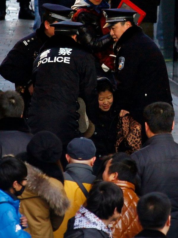 La policía china arrastra a una mujer que se negaba a abandonar la cola para adquirir el iPhone 4S en una de las tiendas Apple