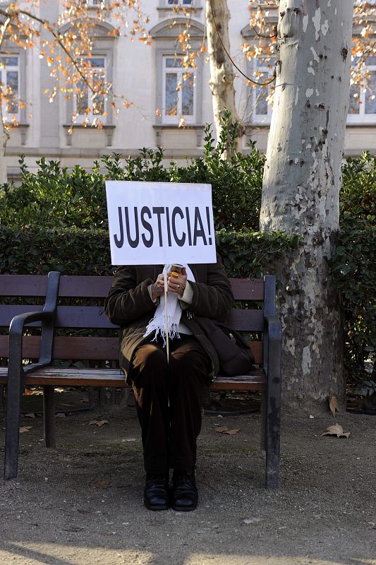Una mujer de las varias decenas que se han concentrado frente al Supremo para apoyar a Garzón, con un cartel de "Justicia" sentada en uno de los bancos.