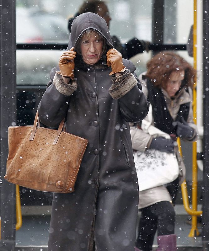 Una mujer de protege del frío y la nieve en Pamplona