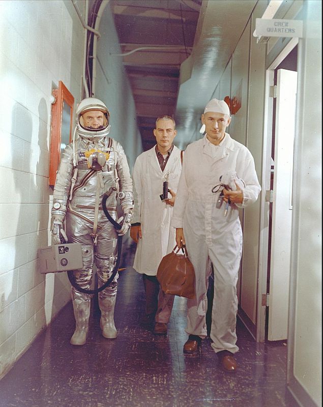 Camino de la plataforma de lanzamiento acompañado por el técnico Joseph W. Schmidt y el médico William Douglas