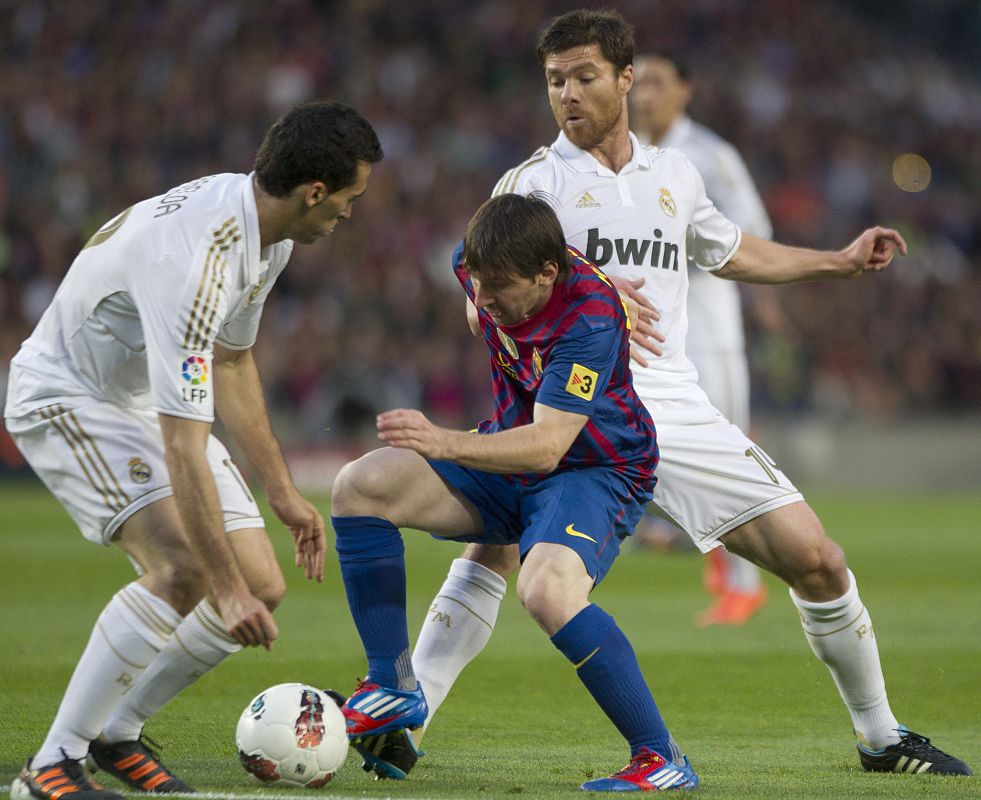 El delantero argentino del FC Barcelona Lionel Messi (c), pelea un balón con el centrocampista Xabi Alonso (detrás) y el defensa alvaro Arbeloa