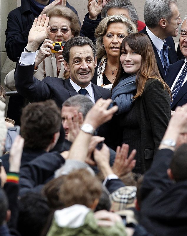 France's President and UMP party candidate for the 2012 French presidential elections Nicolas Sarkozy arrives with France's first lady Carla Bruni-Sarkozy at a voting station in Paris