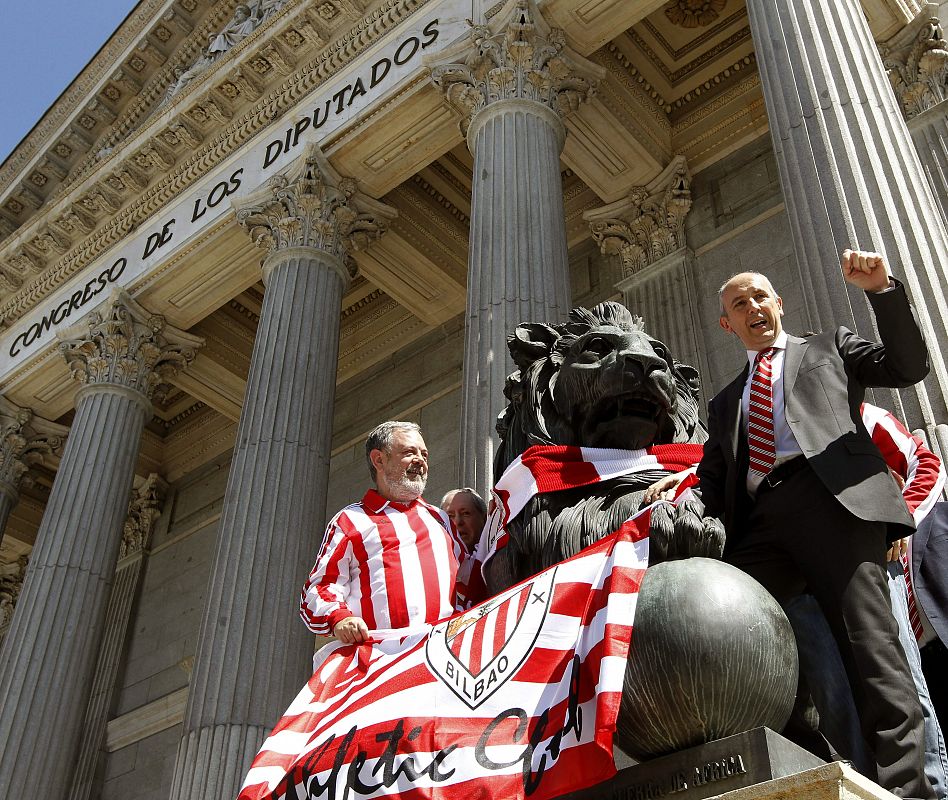 Los diputados del PNV Pedro Azpiazu y Josu Erkoreka posan junto a uno de los leones que preside la entrada principal al edificio del Congreso de los Diputados con banderas del Athletic de Bilbao.