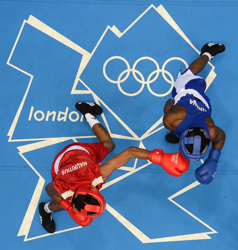 El ganés Duke Micah (a la derecha) se defiende de los golpes del mauriciano Jason Lavigilante en el torneo de boxeo, categoría de peso mosca.