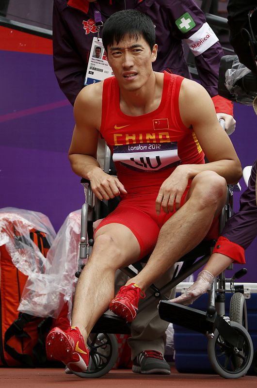 Liu Xiang de China en una silla de ruedas después de lesionarse durante la prueba de carrera con  vallas masculina en la modalidad de 110m. Liu se quedó así, fuera de las eliminatorias en esta prueba.