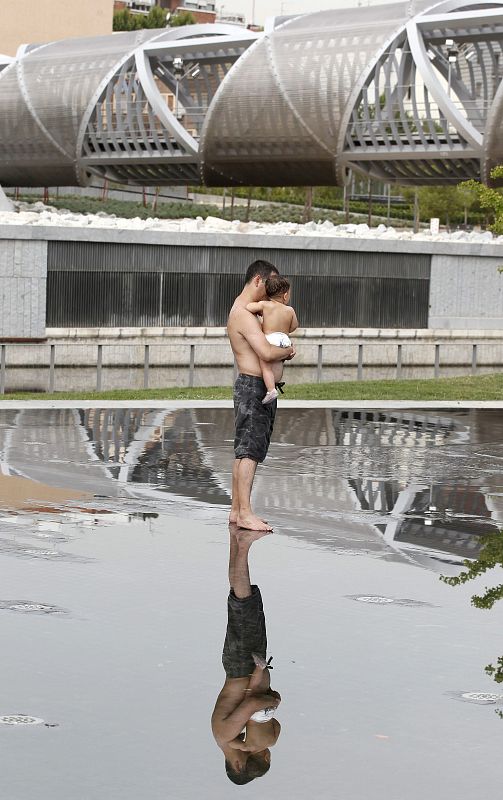 Un hombre sostiene a un niño en brazos en Madrid Rio en un dia en el que las temperaturas alcanzaban los 43 grados