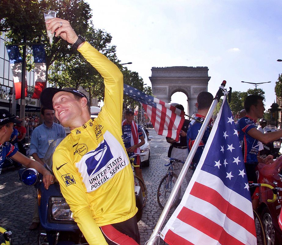 El estadounidense Lance Armstrong, ganador del Tour de Francia en 1999, levantando una copa de champán con la bandera de EE.UU. durante su vuelta de honor en los Campos Elíseos de París.