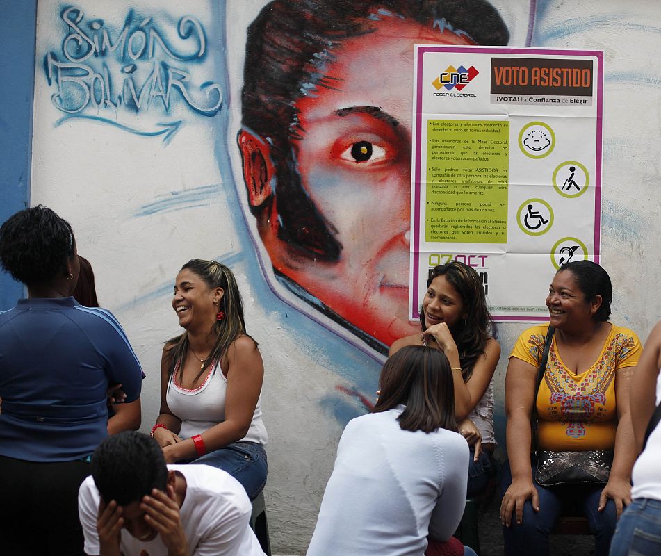 Venezuelans line up in front of mural of Bolivar before casting their vote during the presidential elections in Caracas