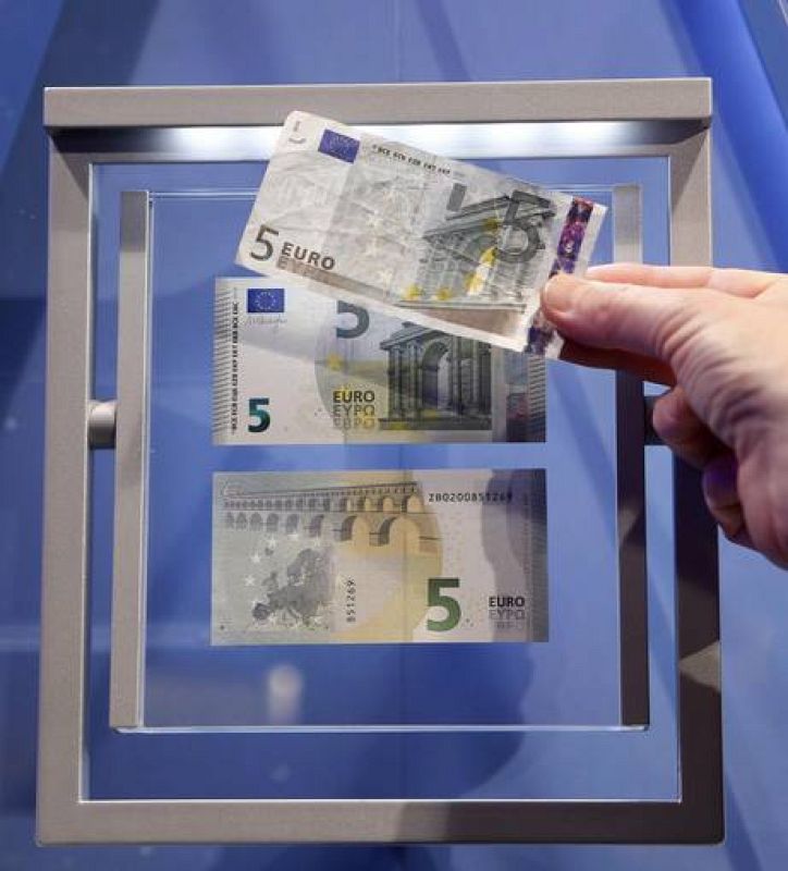 A journalist compares the new 5 euro note with an old one (top) during a ceremony with Draghi, President of the European Central Bank (ECB), in Frankfurt