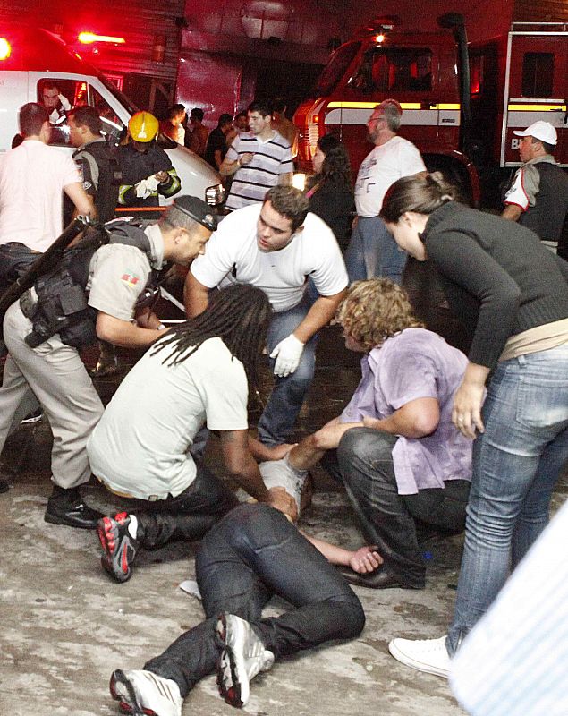 A policeman and rescues workers help a man in front of the Kiss nightclub in the southern city of Santa Maria