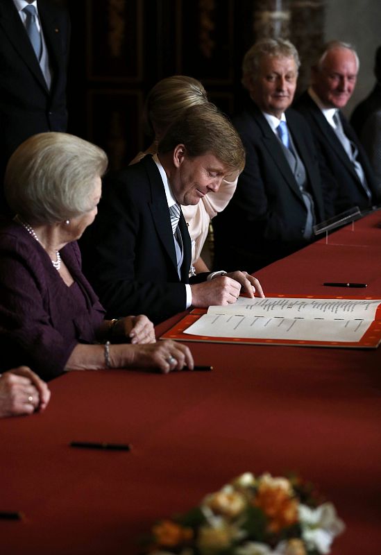 Dutch Crown Prince Willem-Alexander signs the act of abdication of his mother Queen Beatrix during a ceremony at the Royal Palace in Amsterdam