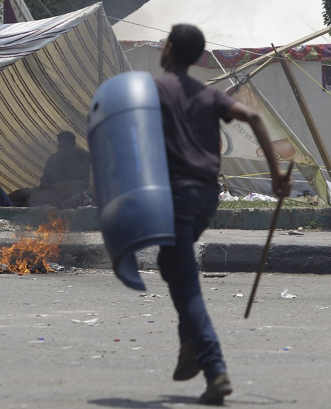 A supporter of President Mursi runs with stick and shield after night clashes with anti-Mursi around Cairo University and Nahdet Misr Square in Giza