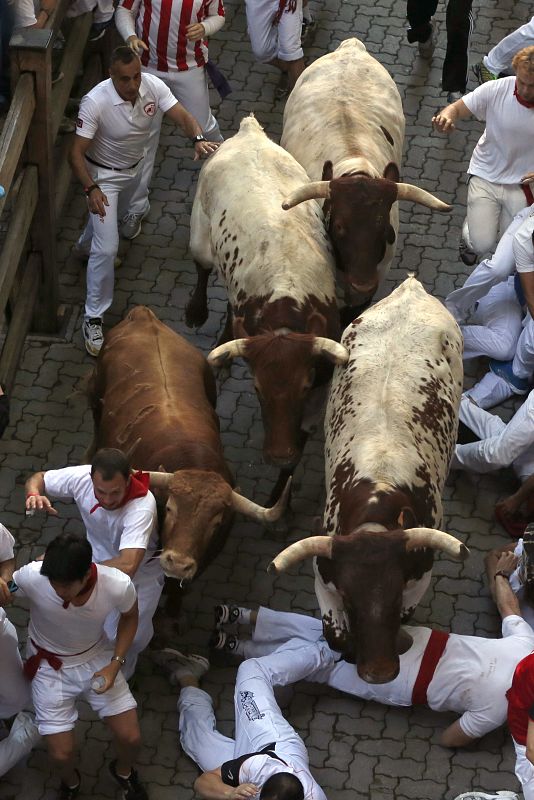 Varios mozos caen ante uno de los toros en el primer encierro de San Fermín.