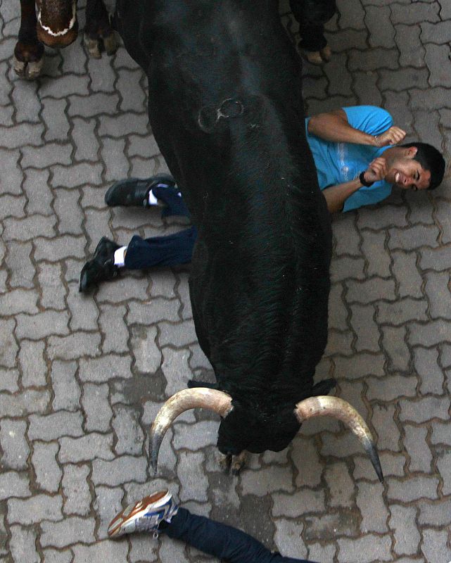 Un toro pasa por encima de un mozo tendido en el suelo a la entrada de la plaza