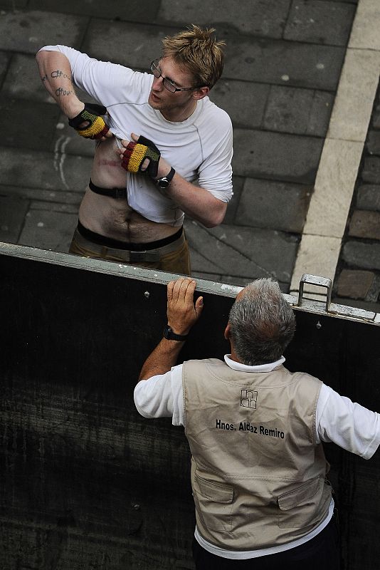 El joven arrollado por la manada en la calle Estafeta muestra a un hombre tras la barrera las marcas del revolcón