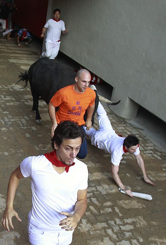 A runner falls in front of a Victoriano del Rio fighting bull at the entrance to the bull ring during the fourth running of the bulls at the San Fermin festival in Pamplona