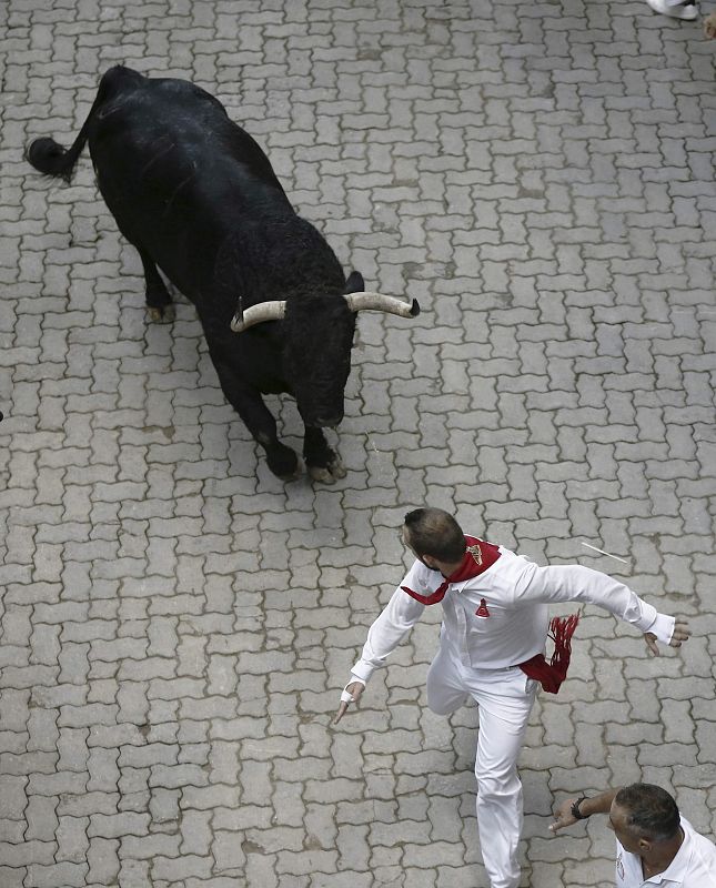 Un mozo corre delante del toro descolgado que ha protagonizado el  peligrosos sexto encierro de San Fermín 2013