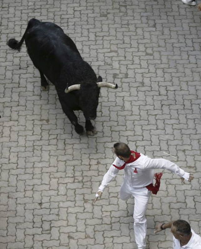 Un mozo corre delante del toro descolgado que ha protagonizado el  peligrosos sexto encierro de San Fermín 2013