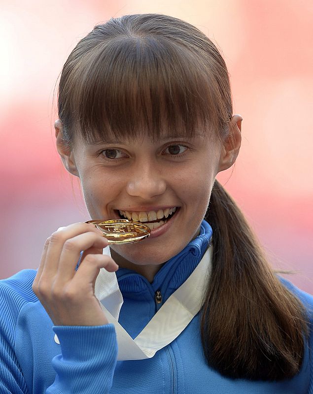 La atleta rusa Elena Lashmanova muerde su medalla de oro en el podio