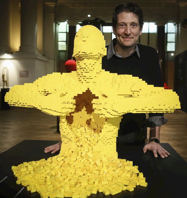 El artista estadounidende Nathan Sawaya posa junto a una escultura realizada con piezas lego titulada "Amarillo", en la exposición "El arte del ladrillo"