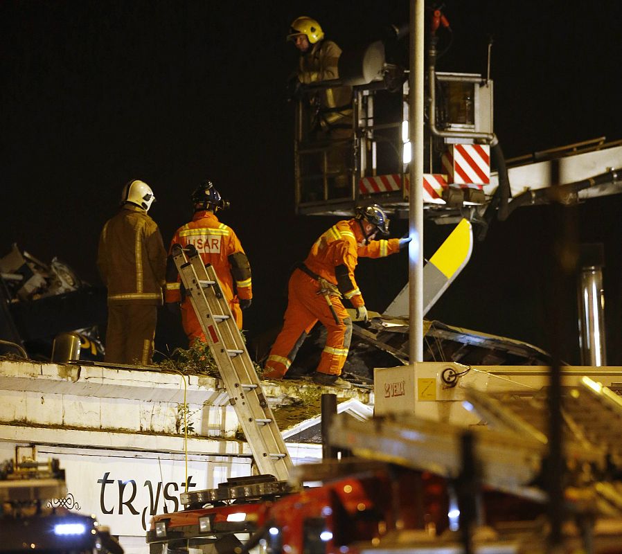 Los equipos de rescate retiran los restos del helicóptero policial que se ha estrellado contra un bar en Glasgow, Escocia