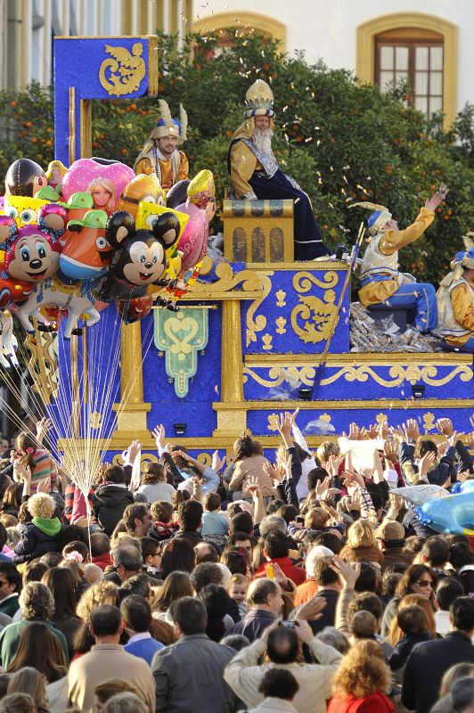 Numeroso público observa el paso del rey Melchor en su carroza dentro de la Cabalgata de los Reyes Magos de Oriente, esta tarde en Sevilla.