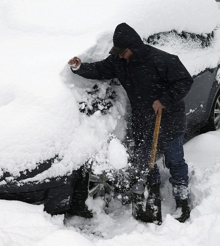 Una persona limpia de nieve su vehículo en Roncesvalles.