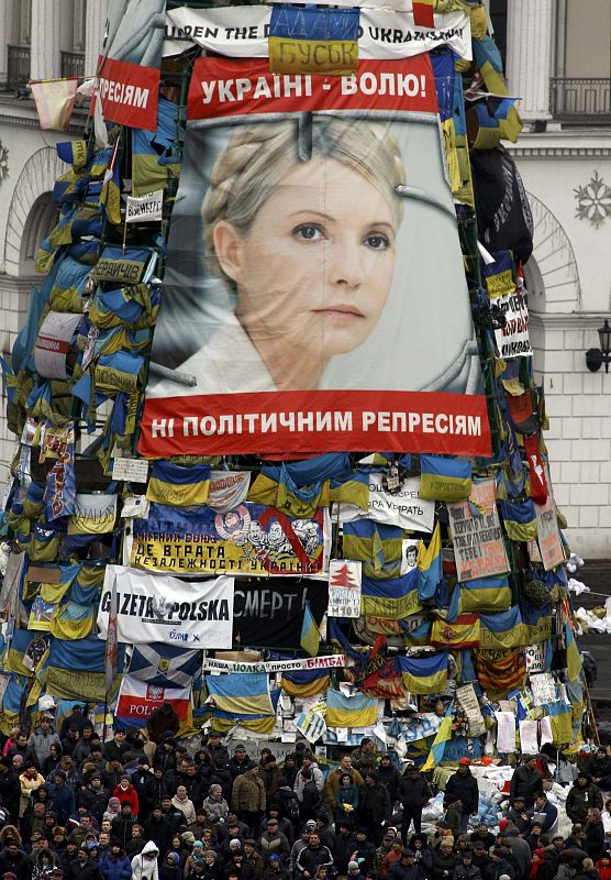 Anti-government protesters stand front of a poster showing jailed Ukrainian opposition leader Yulia Tymoshenko in the Independence Square in Kiev