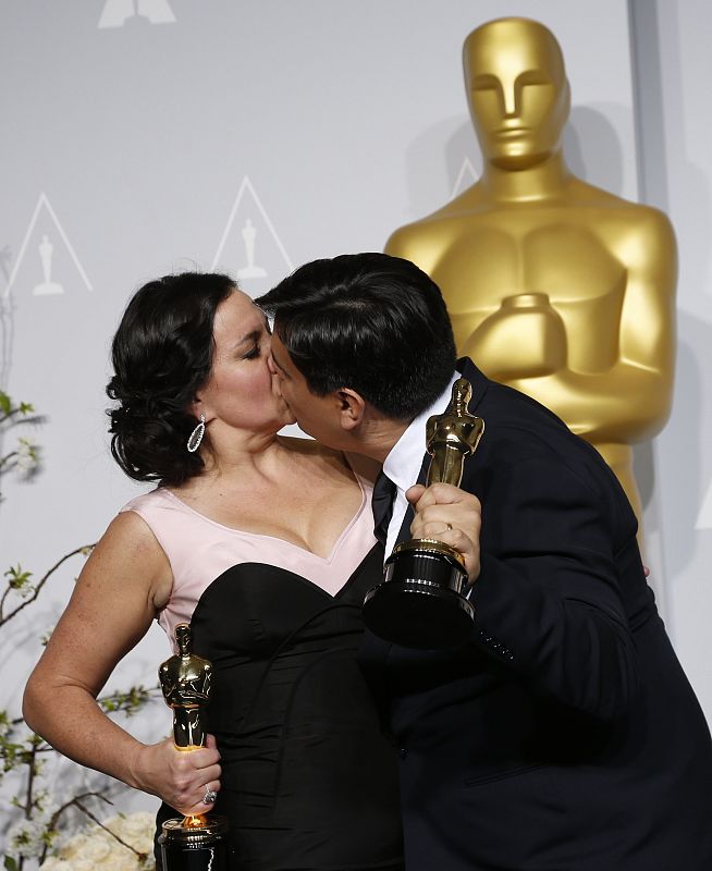 Kristen Anderson Lopez y Robert Lopez se besan sosteniendo su estatuilla a la mejor canción original por "Let it Go" de la película 'Frozen'.