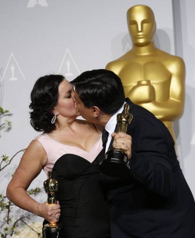 Kristen Anderson Lopez y Robert Lopez se besan sosteniendo su estatuilla a la mejor canción original por "Let it Go" de la película 'Frozen'.