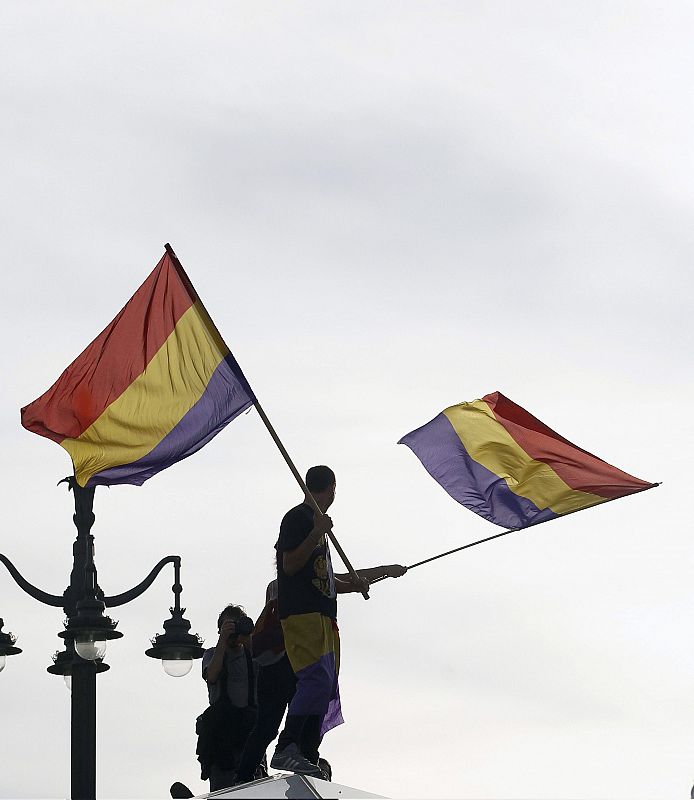 Un manifestante porta banderas republicanas en la Puerta del Sol