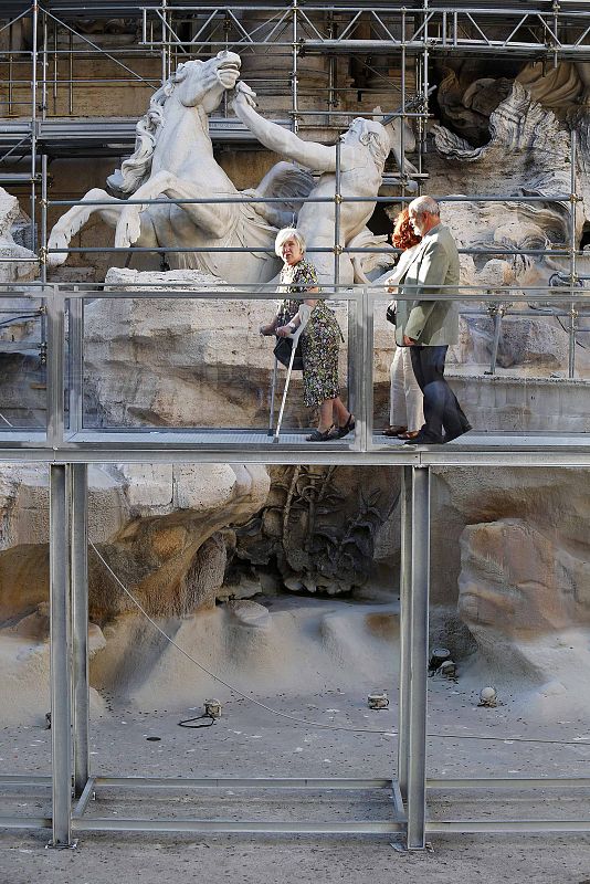 Turistas contemplan la Fontana de Trevi sobre la pasarela instalada durante la restauración