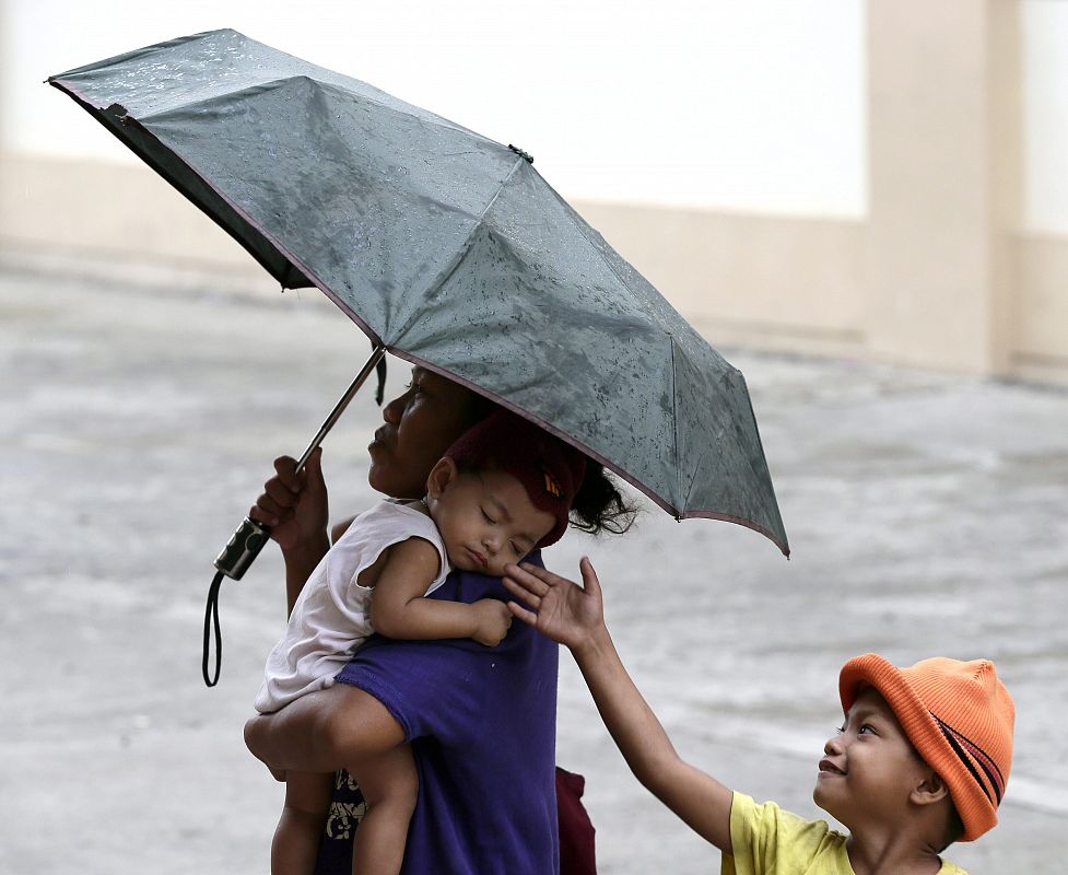 Una mujer traslada a sus hijos hacia un centro de evacuación en un suburbio de Manila