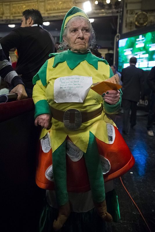 "¡No sabía qué hacer! Soñé que un duende el gordo me iba a traer, así que me disfracé y aquí me presenté", es el mensaje que lleva esta señora, que ha acudido disfrazada al Teatro Real de Madrid.