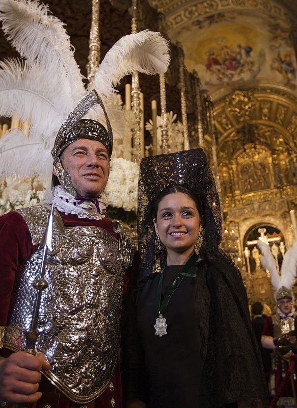 Una joven vestida de mantilla posa junto a un "armao" de la Virgen de la Macarena en Sevilla