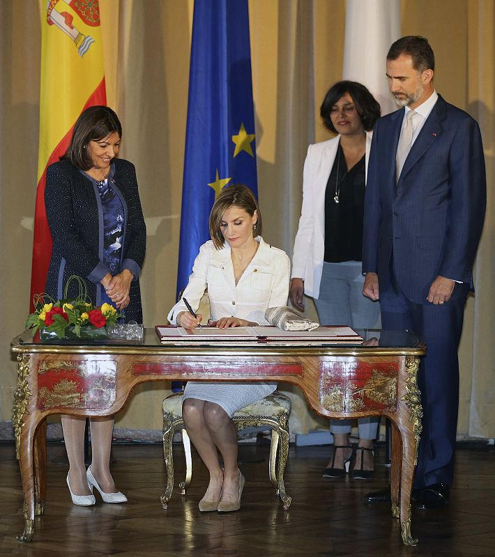 La reina Letizia firma el libro de visitas del Ayuntamiento de París observada por la alcaldesa, Anne Hidalgo y el rey Felipe VI.