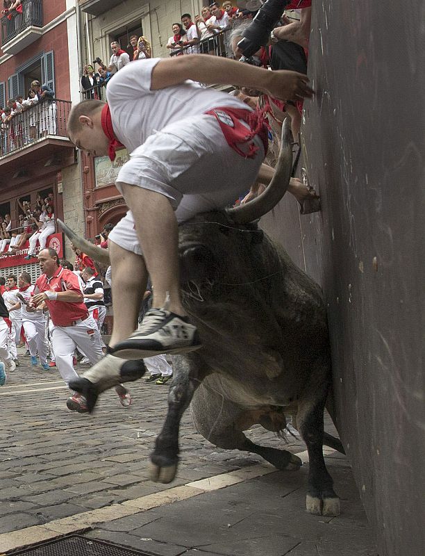 Un toro empuja a uno de los corredores en la curva de Mercaderes