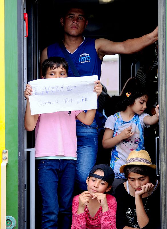 "Necesito ir a Alemania para vivir", se lee en carteles sostenidos por jóvenes migrantes en un tren en la estación de Bickse en Hungría