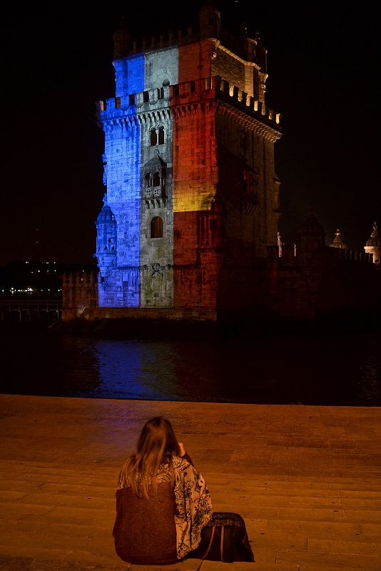 Una mujer observa la Torre de Belén, en Lisboa, pintada con los colores de Francia