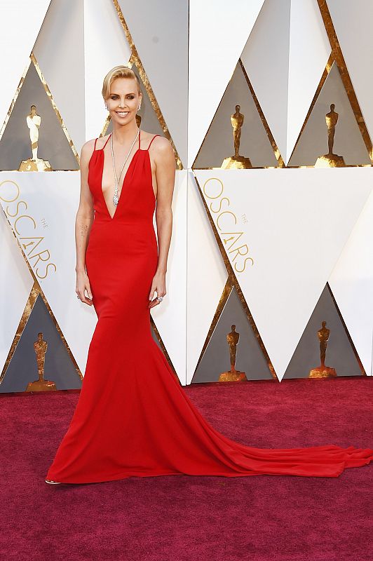 Sencilla con Valentino rojo ha lucido Charlize Theron sobre la pasarela de los Oscar.