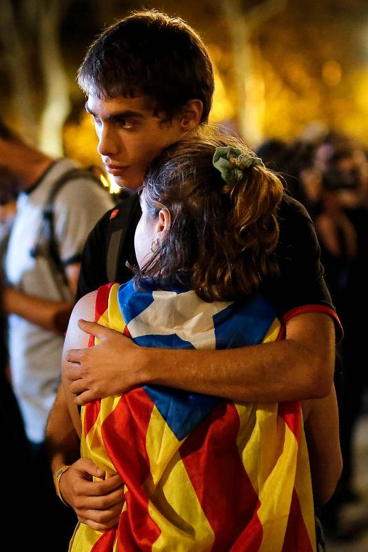 Una pareja se abraza mientras ve el discurso de Puigdemont en las pantallas 