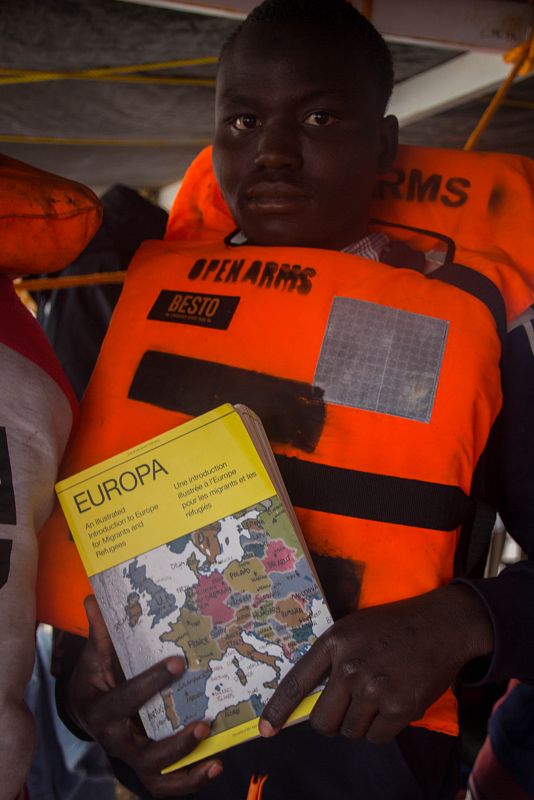 Un joven subsahariano posa con una Europa: Introducción ilustrada para migrantes y refugiados en versión trilingüe: inglés, francés y árabe. Dice que es muy importante para él.
