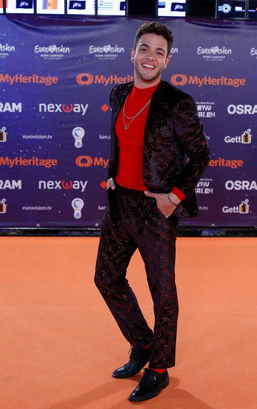 Luca Hanni posa en la alfombra naranja con un traje con mucho "brilli-brilli" y camiseta roja