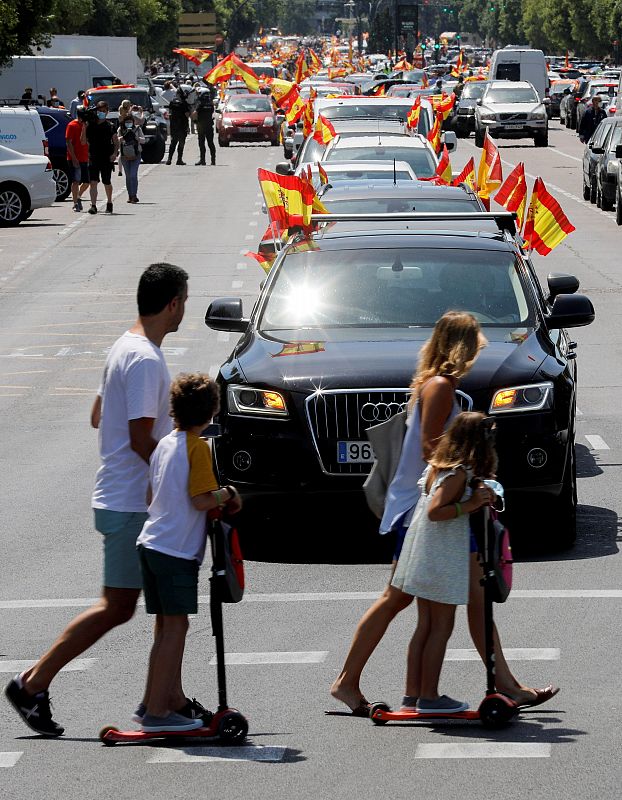 Una familia contempla en Valencia la manifestación motorizada contra la política del Gobierno convocada por Vox.