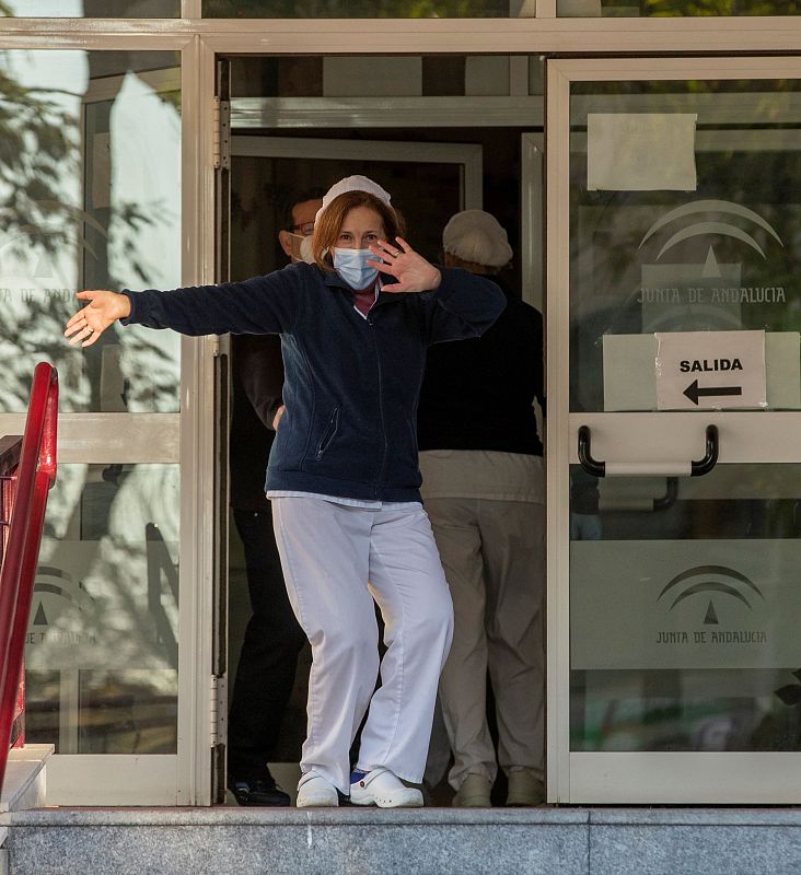 Una cuidadora del Centro para Personas Mayores de Heliópolis en Sevilla bailando al son de la música de la megafonía mientras espera en la puerta de esta residencia pública la llegada de la vacuna