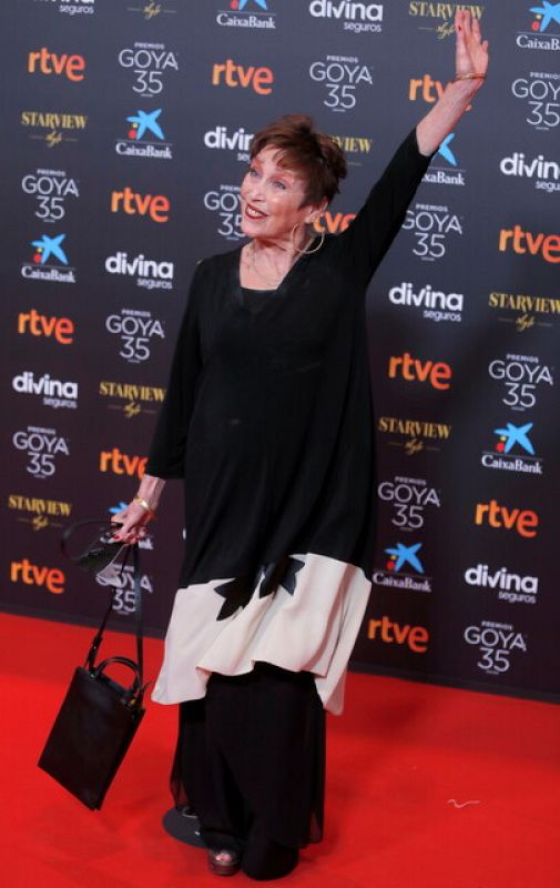 La actriz saluda sobre la alfombra con un vestido vaporoso en blanco y negro.