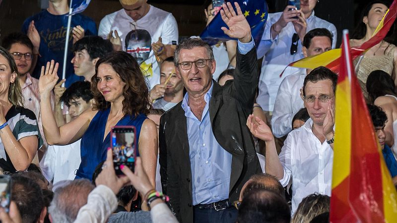 Feijóo, Ayuso y Almeida durante un acto en Madrid bajo la lluvia